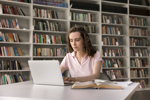 Woman sitting at desk in a library in front of computer